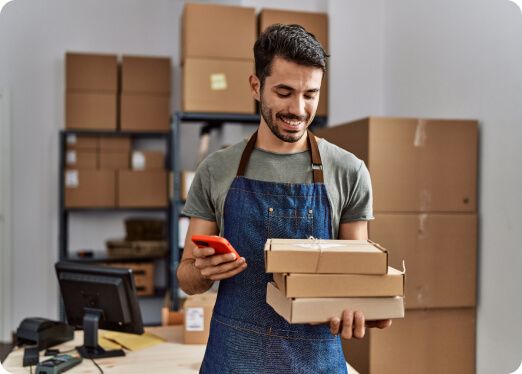 Intermedeie as transações financeiras para o seu negócio. Uma pessoa segurando caixas de papelão e um celular.
