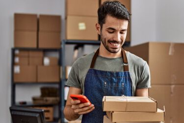 Intermedeie as transações financeiras para o seu negócio. Uma pessoa segurando caixas de papelão e um celular.